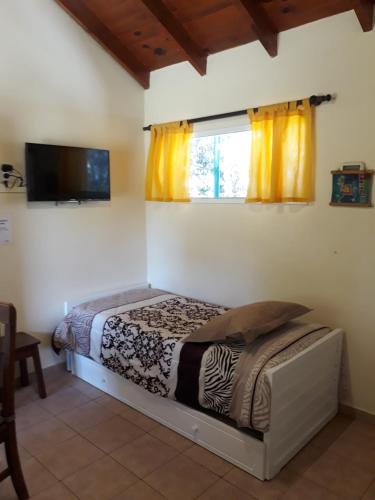 a bedroom with a bed and a window with yellow curtains at Pa-kuas del Uritorco in Capilla del Monte