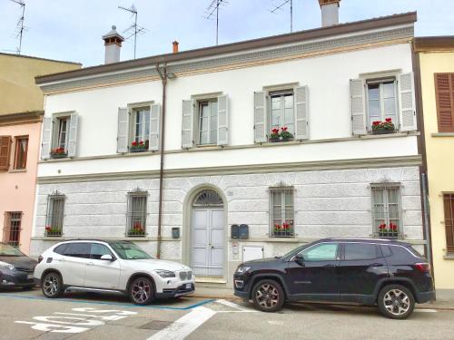 due auto parcheggiate di fronte a un edificio bianco di La Maison B&B a Lugo