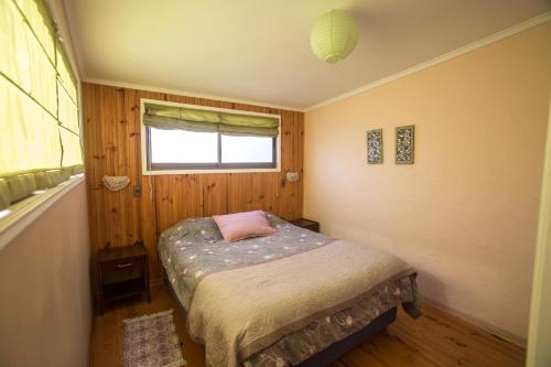 a small bedroom with a bed and a window at Cabañas Piedra Grande in Pichilemu
