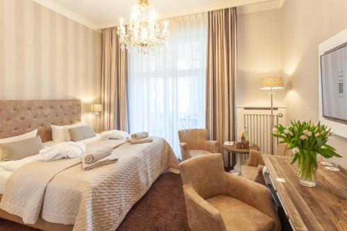 a bedroom with a large bed and a chandelier at Hotel Vier Jahreszeiten Binz - Adults Only in Binz