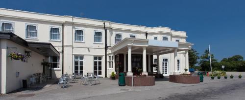a white building with tables and chairs in front of it at Russ Hill Hotel in Charlwood