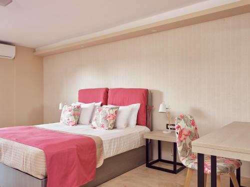 a bedroom with a bed with a pink headboard and a table at Koukounaria Hotel & Suites in Alykes