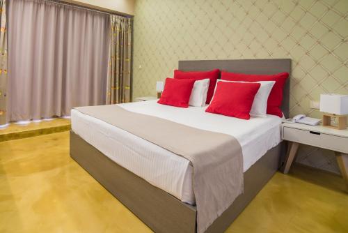 a bedroom with a large bed with red pillows at Koukounaria Hotel & Suites in Alykes