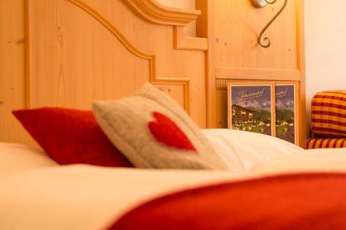 a bed with a pillow with a red flower on it at Berghotel Johanneshof in Anterselva di Mezzo
