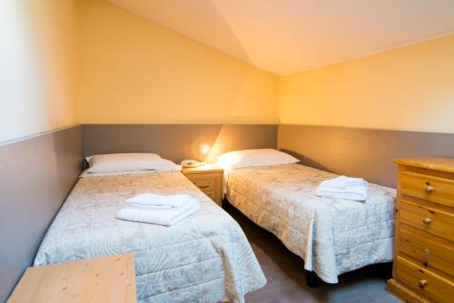 two beds in a room with yellow walls at Hotel Alla Fonte in Arta Terme