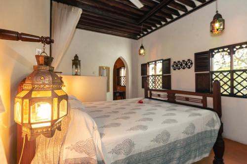 a bedroom with a bed with a lamp on it at Kijani Hotel in Lamu