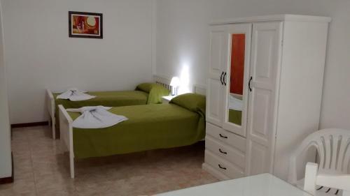 a bedroom with two beds and a white cabinet at Las Casuarinas in Pilar