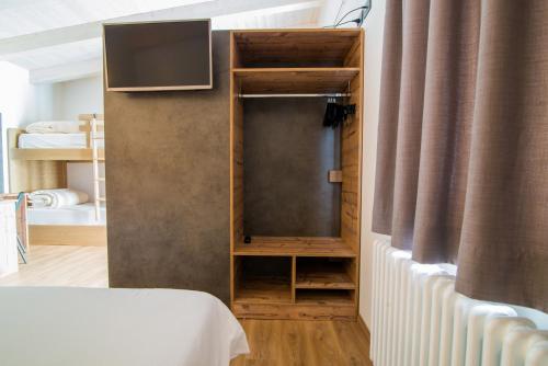 a room with a bed and a tv on a wall at Hotel Alla Fonte in Arta Terme