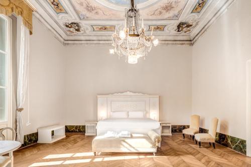 a white bedroom with a bed and a chandelier at Palazzo D'Oltrarno - Residenza D'Epoca in Florence