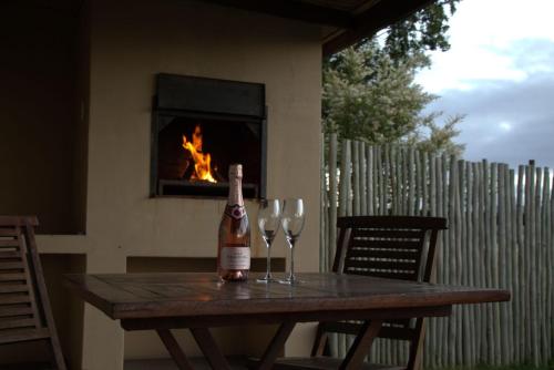 a bottle of wine sitting on a table with two wine glasses at Wild Clover Cottages in Stellenbosch
