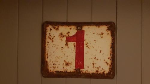 a rusty sign with the number one on a wall at Le Vieux Logis de la Galocherie in Sainte-Florence