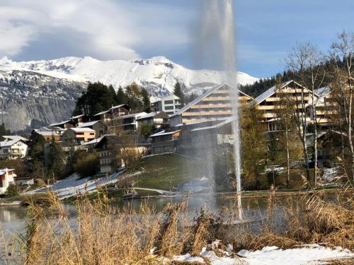a water fountain in front of a town with snow covered mountains at Laax Rancho Residence in Laax