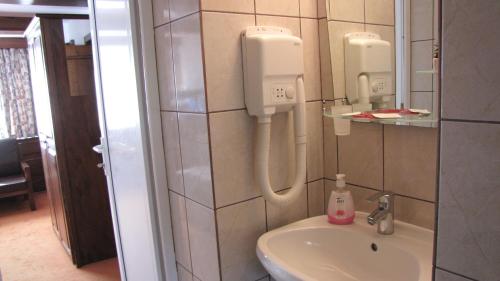 a bathroom with a sink and a soap dispenser on the wall at Villa Elitte Predeal in Predeal