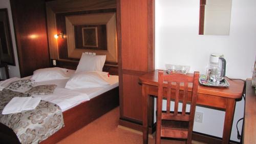 a small bedroom with a bed and a desk with a table at Villa Elitte Predeal in Predeal