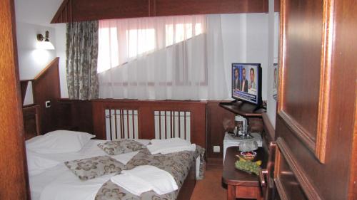 a hotel room with two beds and a television at Villa Elitte Predeal in Predeal