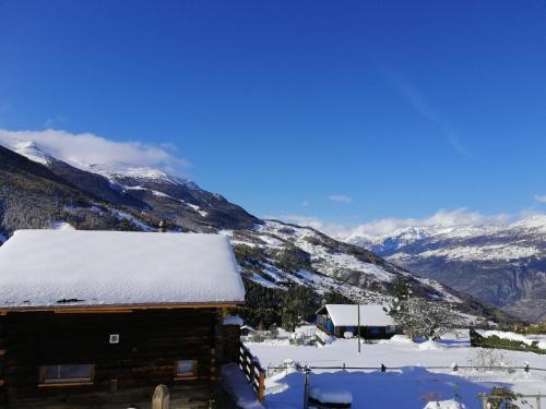 a cabin covered in snow with mountains in the background at "forno one" - Bürchen Moosalp in Bürchen