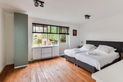 1 dormitorio con 2 camas y ventana en Luxury Garden View Apartment, en Zandvoort