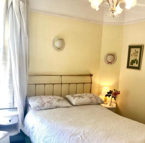 ein Schlafzimmer mit einem Bett, einem Kronleuchter und einem Fenster in der Unterkunft Lauras Townhouse Apartments Erte's Atelier in Bath