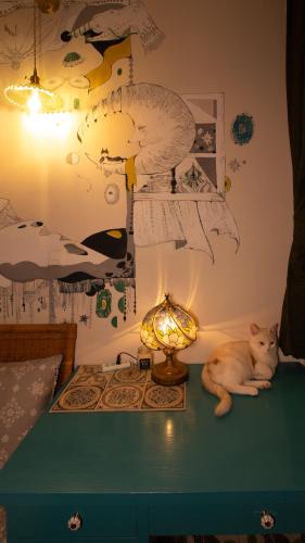 a cat laying on a table next to a lamp at Red Letter Day in Tainan