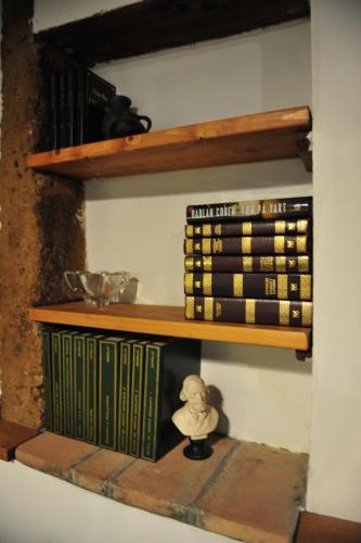 a shelf with books on it with a doll on it at Casa Messi in Pitigliano