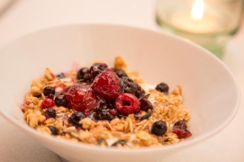 a white bowl of cereal with berries and fruit at Estalagem de Monsaraz in Monsaraz