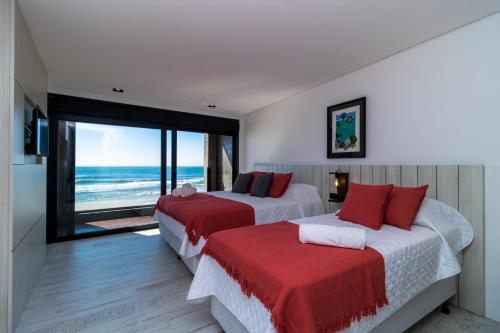 two beds in a room with a view of the ocean at BALUARTE POUSADA in Torres
