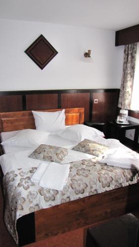 a bed with white sheets and a wooden head board at Villa Elitte Predeal in Predeal