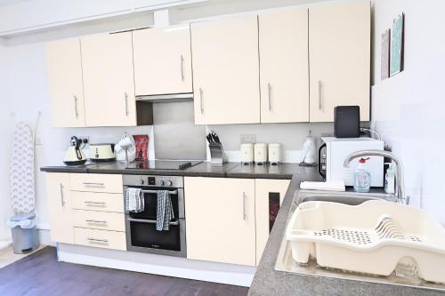 a white kitchen with white cabinets and appliances at Whitburn Guest House About 7 mins Walk To The City Free Internet TV in Doncaster