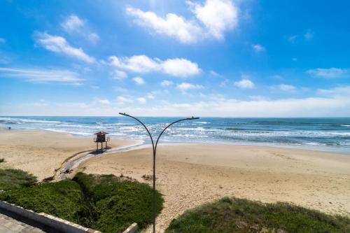 a person standing on a beach near the ocean at BALUARTE POUSADA in Torres