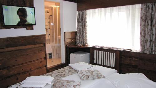 a bedroom with a bed with a tv on the wall at Villa Elitte Predeal in Predeal