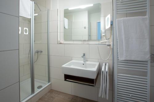 a white bathroom with a sink and a shower at Stadthaushotel Hamburg - Inklusionshotel in Hamburg