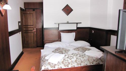 a bedroom with a bed with white sheets and pillows at Villa Elitte Predeal in Predeal