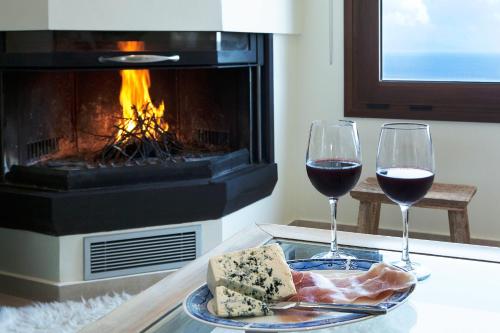 two glasses of wine and cheese on a table in front of a fireplace at Paganea's House in Paganéa