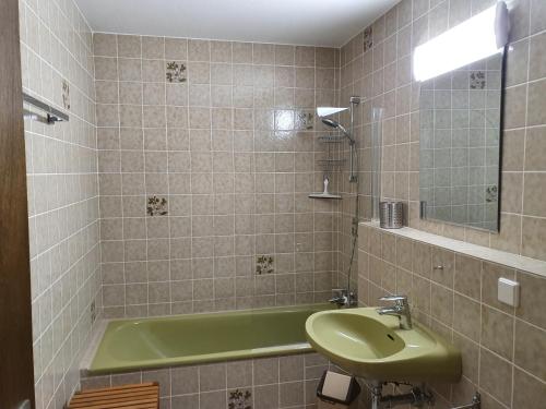 La salle de bains est pourvue d'un lavabo vert et d'une baignoire. dans l'établissement Ferienwohnung Nicole, à Missen-Wilhams
