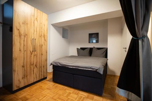 ein kleines Schlafzimmer mit einem Bett und einem Holzschrank in der Unterkunft Apartment Ilaria in Tuttlingen
