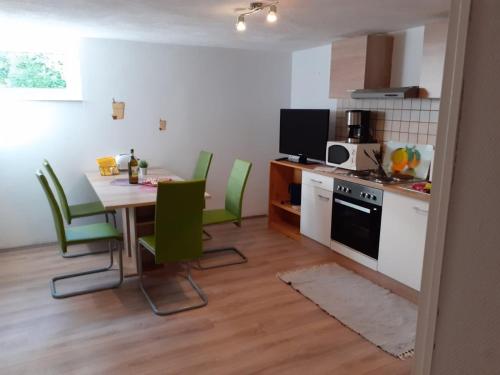 eine Küche und ein Esszimmer mit einem Tisch und grünen Stühlen in der Unterkunft Souterrain Apartment Laatzen in Hannover