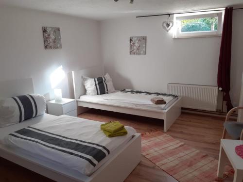 Habitación blanca con 2 camas y ventana en Souterrain Apartment Laatzen, en Hannover