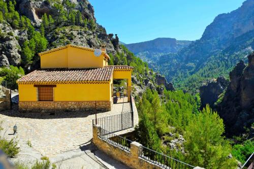 un bâtiment jaune sur le côté d'une montagne dans l'établissement Casas Rurales Mirador del Rio Zumeta, à Santiago de la Espada