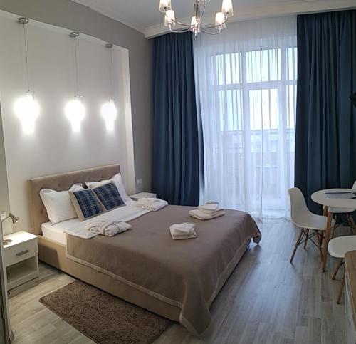 a bedroom with a bed with blue curtains and a table at Kharkov & Apartments in the city center in Kharkiv