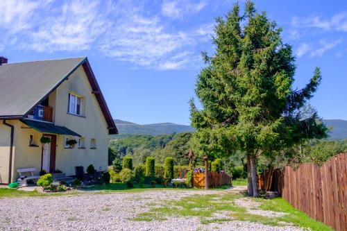 una casa con un árbol al lado de una valla en Kwatery u Anety en Ustrzyki Górne