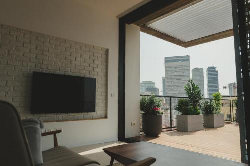 a living room with a flat screen tv on a brick wall at The Rambam Residence - By Localz Group in Tel Aviv