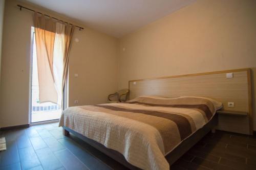ein Schlafzimmer mit einem Bett und einem großen Fenster in der Unterkunft Apartments Ribarica in Karlobag