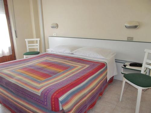 a bedroom with a bed with a colorful blanket on it at Albergo Giglio in Chianciano Terme