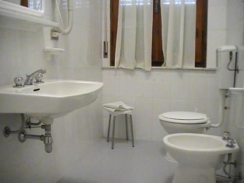 a white bathroom with a sink and a toilet at Albergo Giglio in Chianciano Terme