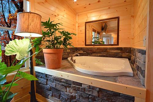 a bath tub in a wooden room with a mirror at #820 Honeymoon Hideaway in Gatlinburg