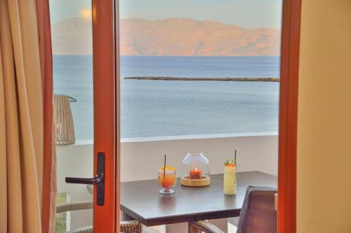a table with two candles on it with a view of the ocean at Maria Beach Hotel in Kissamos