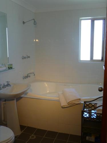 a white bathroom with a tub and a sink at Park Ridge Retreat in Gerringong