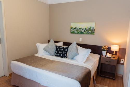 a bedroom with a large bed with pillows on it at Hotel Itajara in Jaraguá do Sul