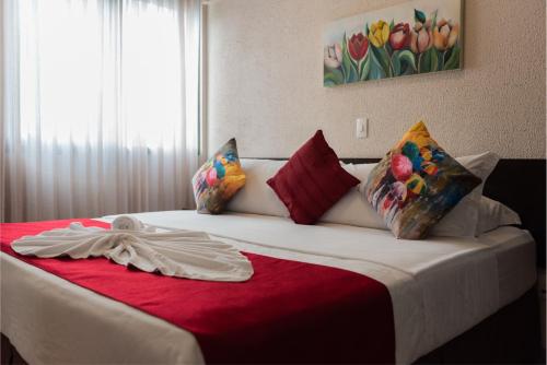 1 dormitorio con 1 cama con manta roja en Hotel Itajara, en Jaraguá do Sul