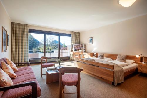 ein Hotelzimmer mit einem Bett und einem Sofa sowie einem Wohnzimmer in der Unterkunft Aparthotel Andreas Hofer in Kufstein